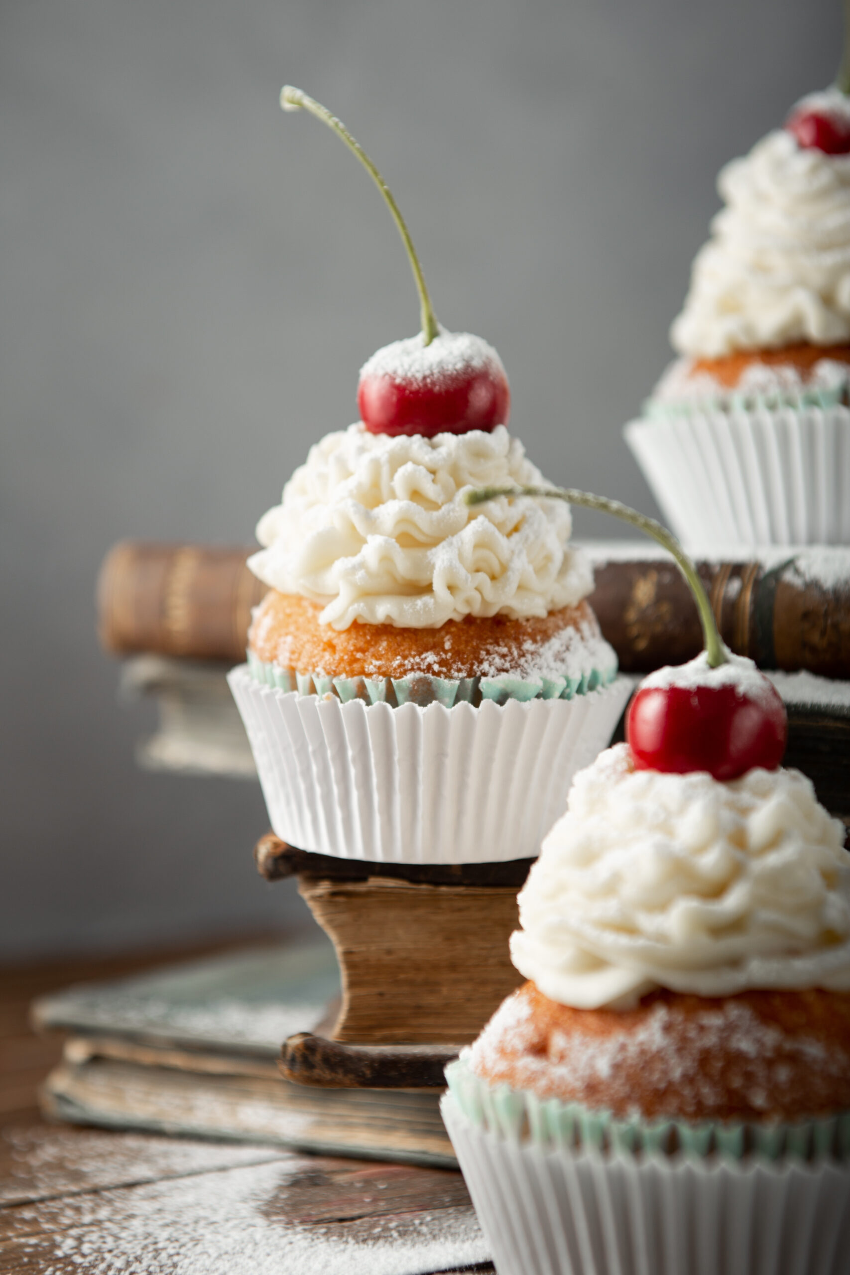 Vertical Shot Delicious Cupcakes With Cream Powdered Sugar Cherry Top Books Scaled